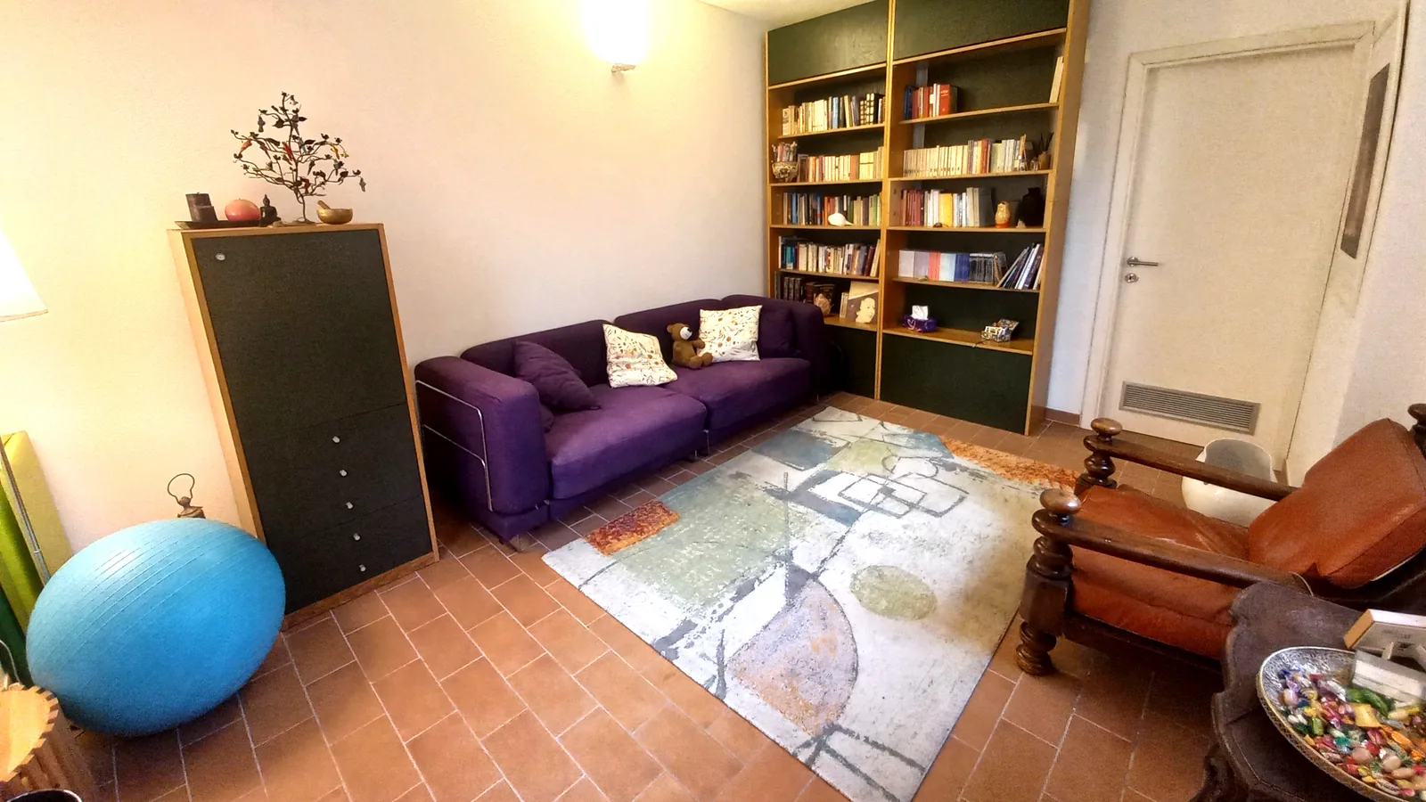 Lo studio di Marzia Risi, con divano viola, poltrona e libreria